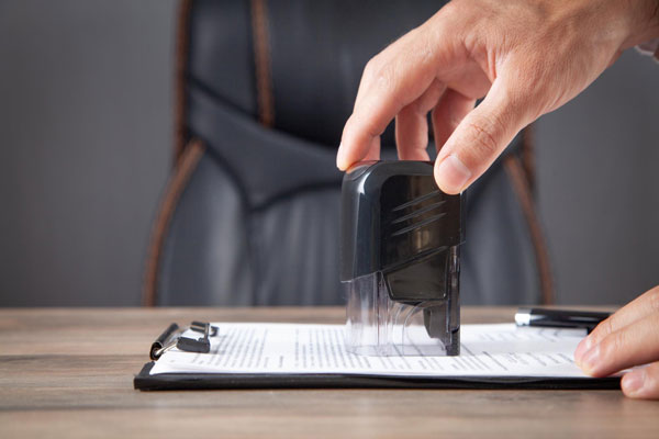 A person stamps a document using a stamper.