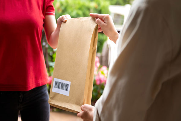 A woman passing a package to another woman, symbolizing a gesture of exchange or delivery.