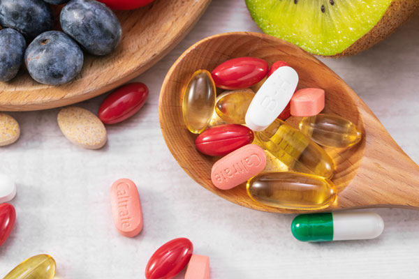 Various vitamins and supplements on a wooden spoon.