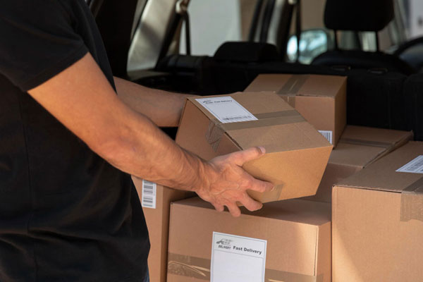 A man opening a box in the back of a car.